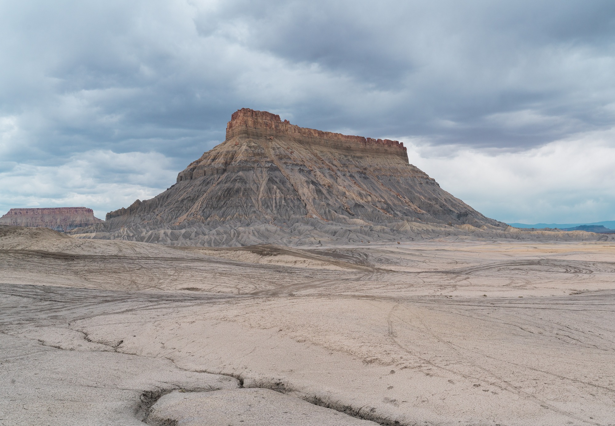 Factory Butte rises above an expansive gray desert landscape in Utah.