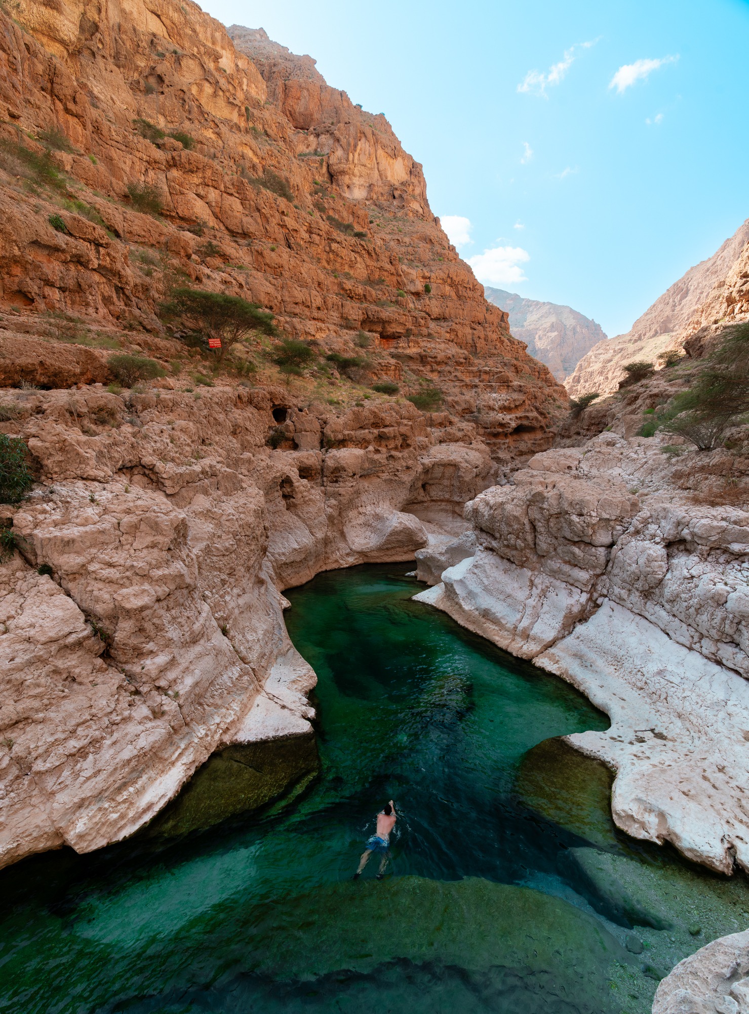 Clear emerald pools wind between canyon walls at Wadi Shab, Oman.