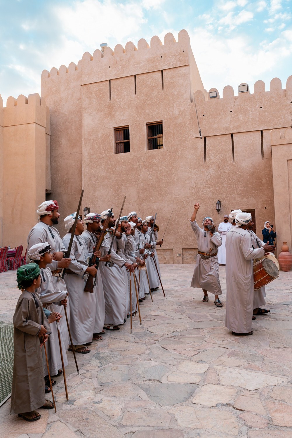 A gathering in traditional dress fills the courtyard of Nizwa Fort, Oman.